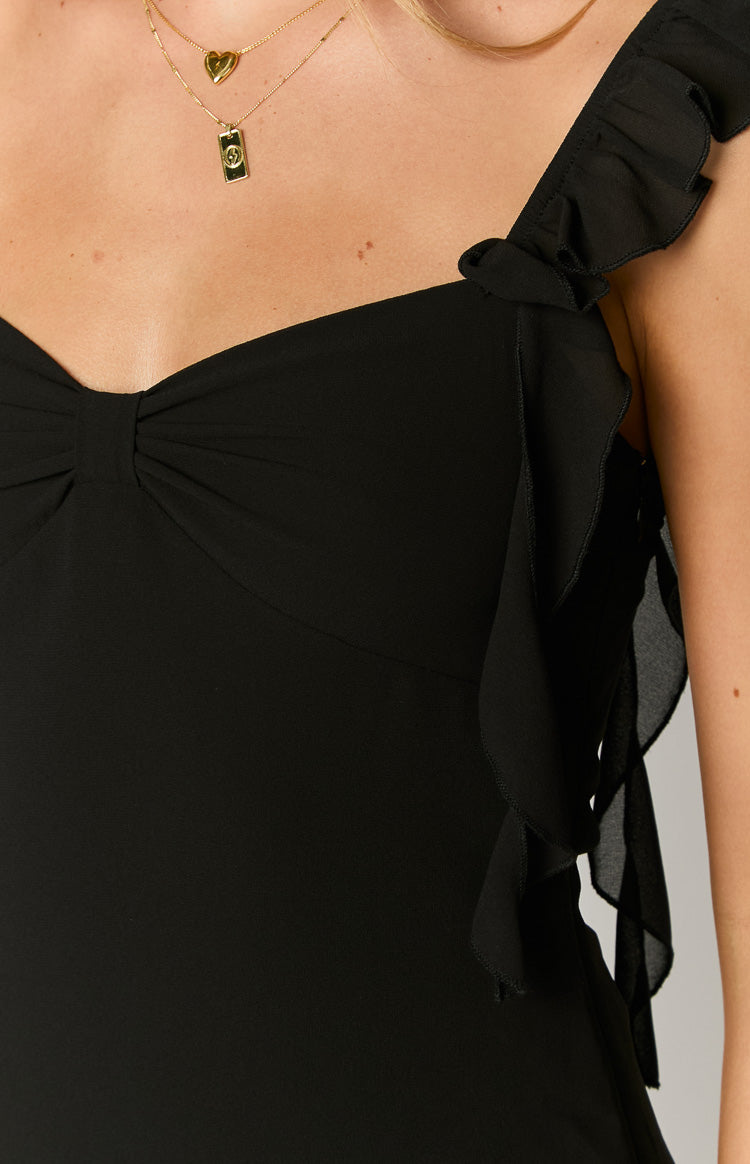Close-up of the ruffled shoulder strap and ruched sweetheart neckline on a black chiffon mini dress