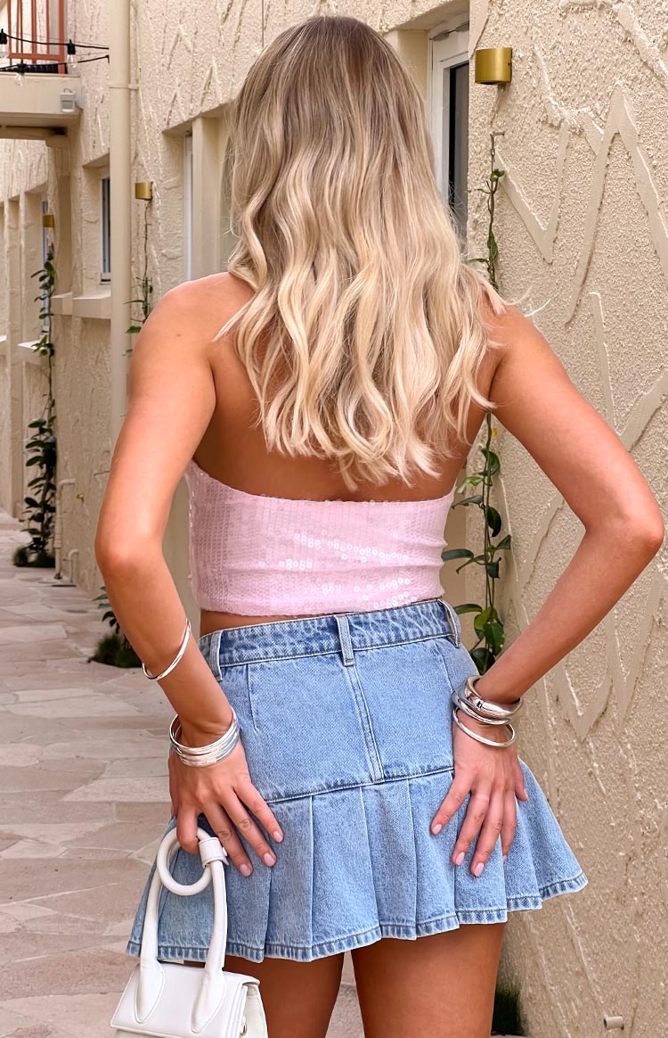 Rear view of a light wash pleated denim mini skirt with a full pleated hem and back waistband