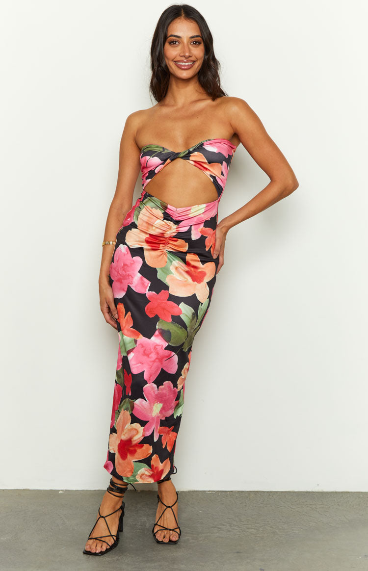 Front view of a black floral midi dress with a strapless twisted bodice, midriff cutout, and ruched waist detail