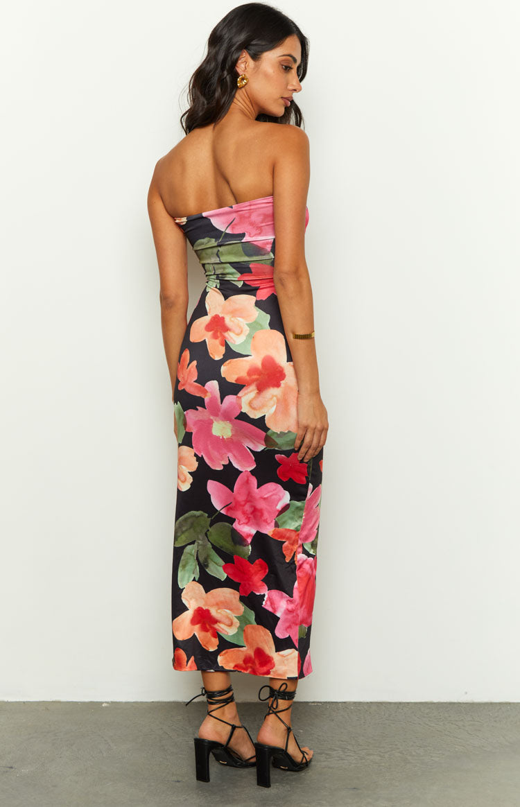 Side view of a black floral midi dress with ruched side detail and vibrant pink and orange floral print