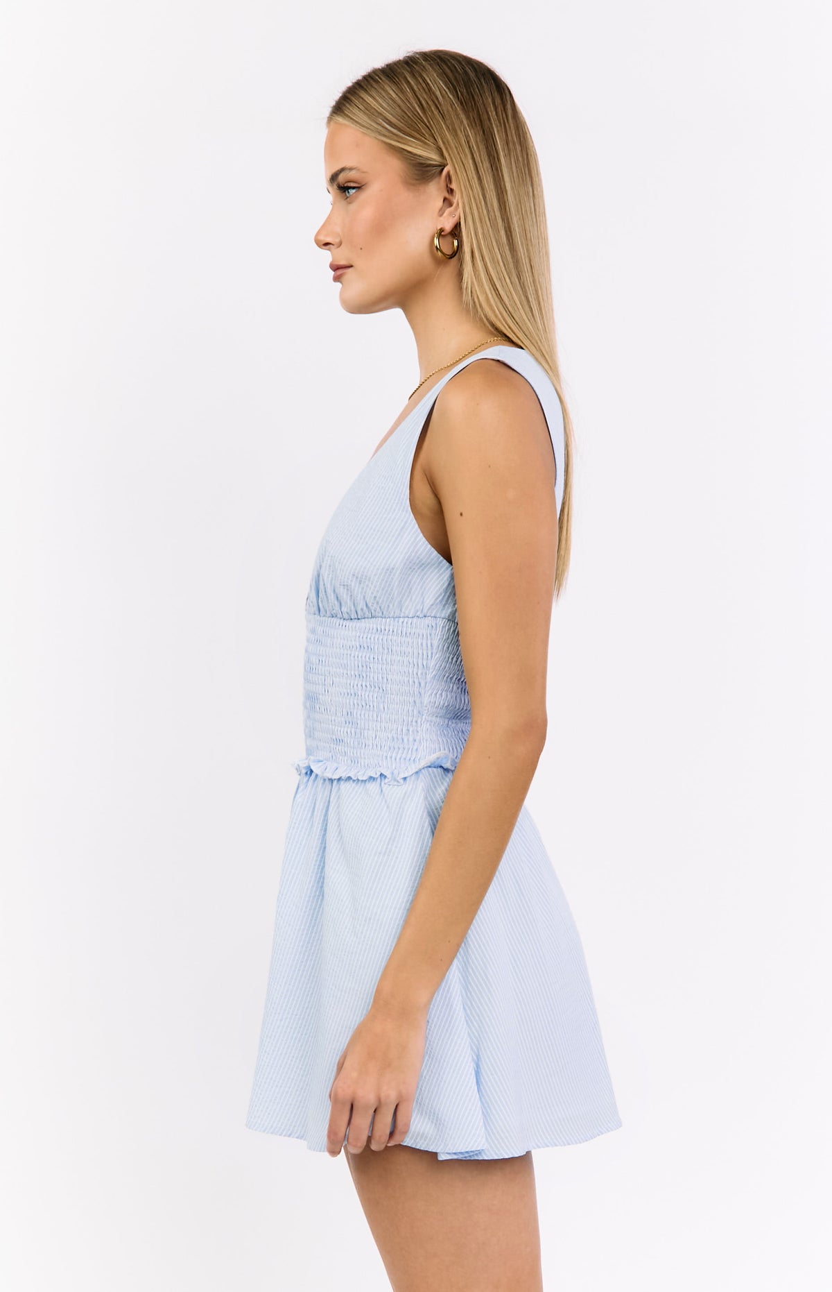 Side view of the light blue stripe mini dress with a shirred bodice and V-neckline