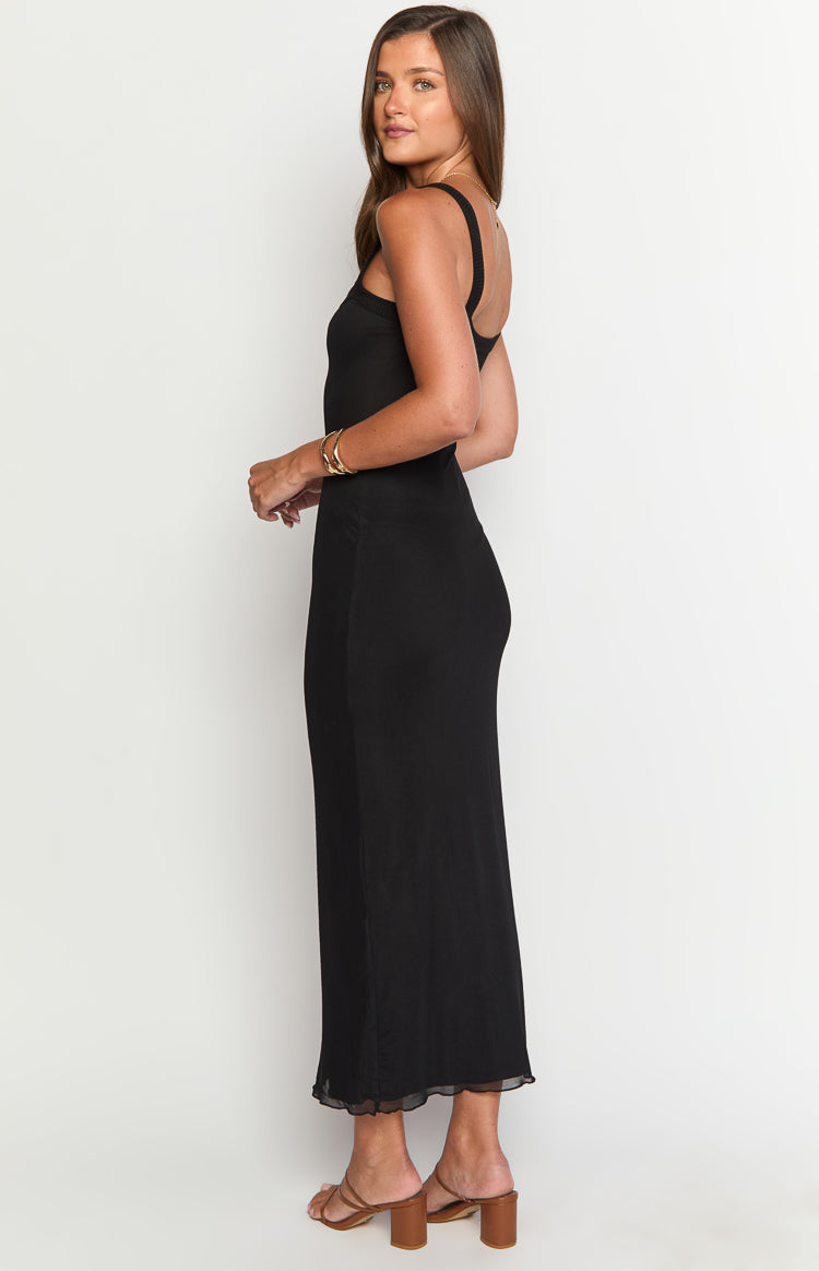 Side view of a black fitted maxi dress with thin straps and a sheer ruffled hem