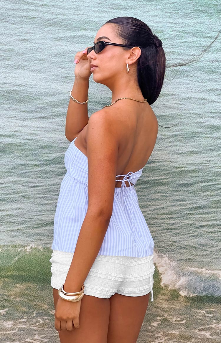 Side view of the light blue and white striped strapless top with a cinched tie-back and flared peplum hem