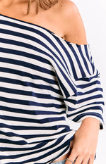 Close-up of the off-shoulder neckline and relaxed long sleeve of the navy and white striped top