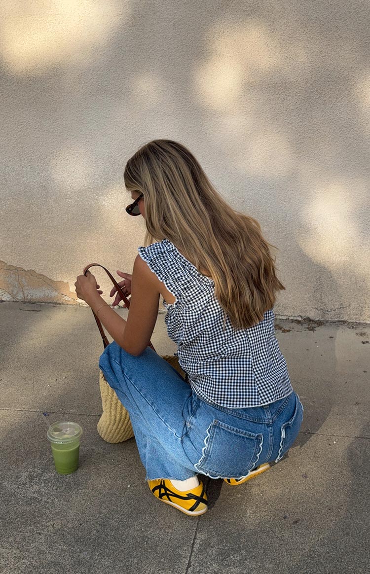 Rear view of mid wash blue jeans with white scalloped trim on the back pockets