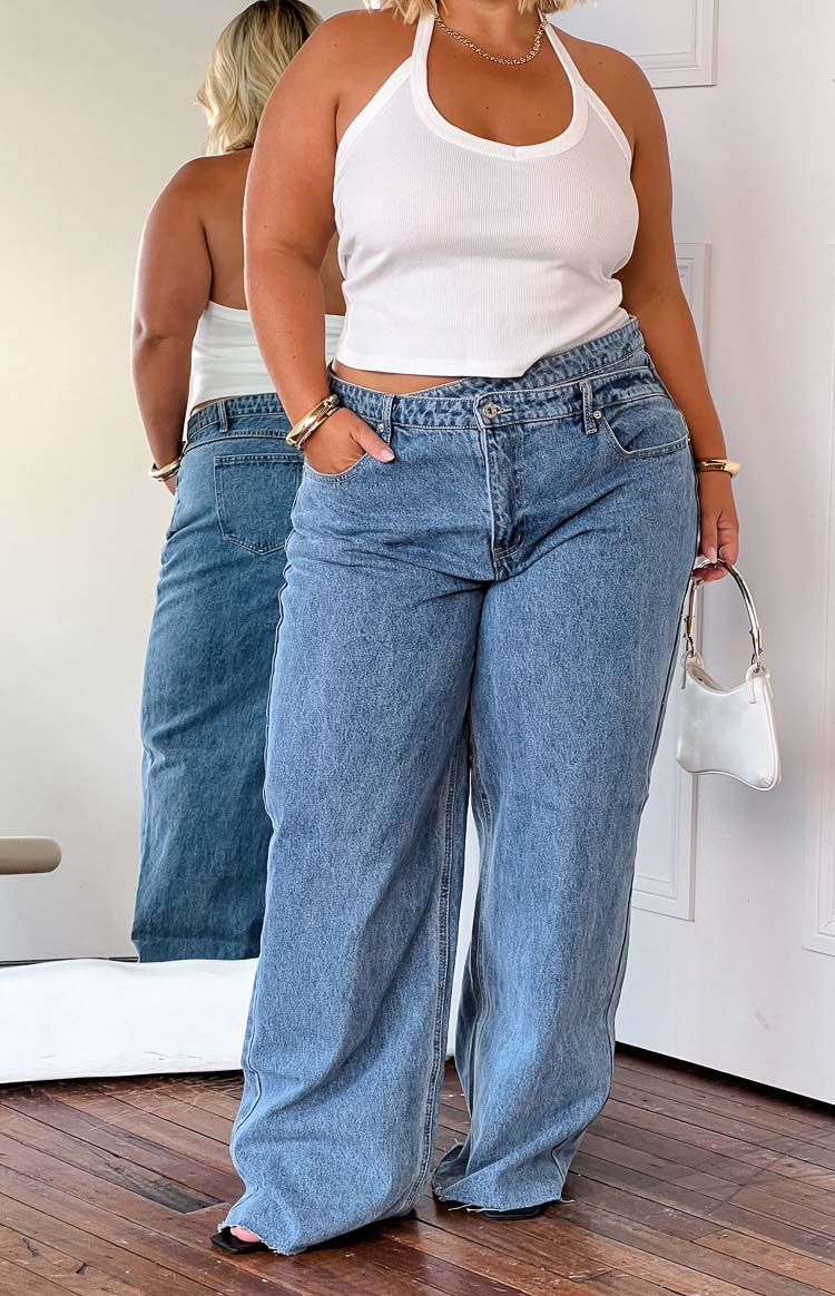 Front view of blue wide-leg jeans with an uneven crossover waist and relaxed fit