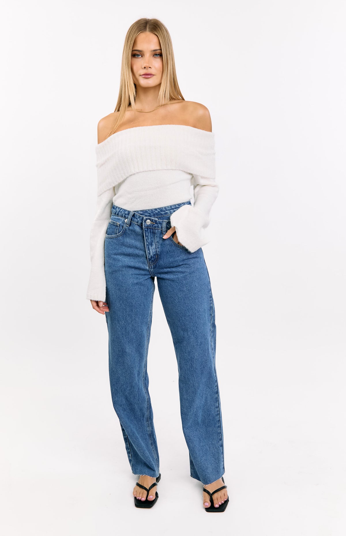 Front view of mid wash jeans with an uneven crossover waist and straight leg fit