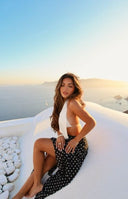A white ribbed halter neck tank top paired with a black midi skirt featuring white polka dots and a stylish handkerchief hem- ideal for a breezy casual outfit.