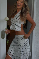 Side view of a white polka dot hanky hem midi skirt with a flowy silhouette