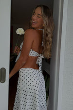 Side view of a white polka dot midi skirt with a flowy hanky hem and subtle side zipper detail
