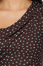 Close-up of the draped brown polka dot fabric showing the off-shoulder neckline detail