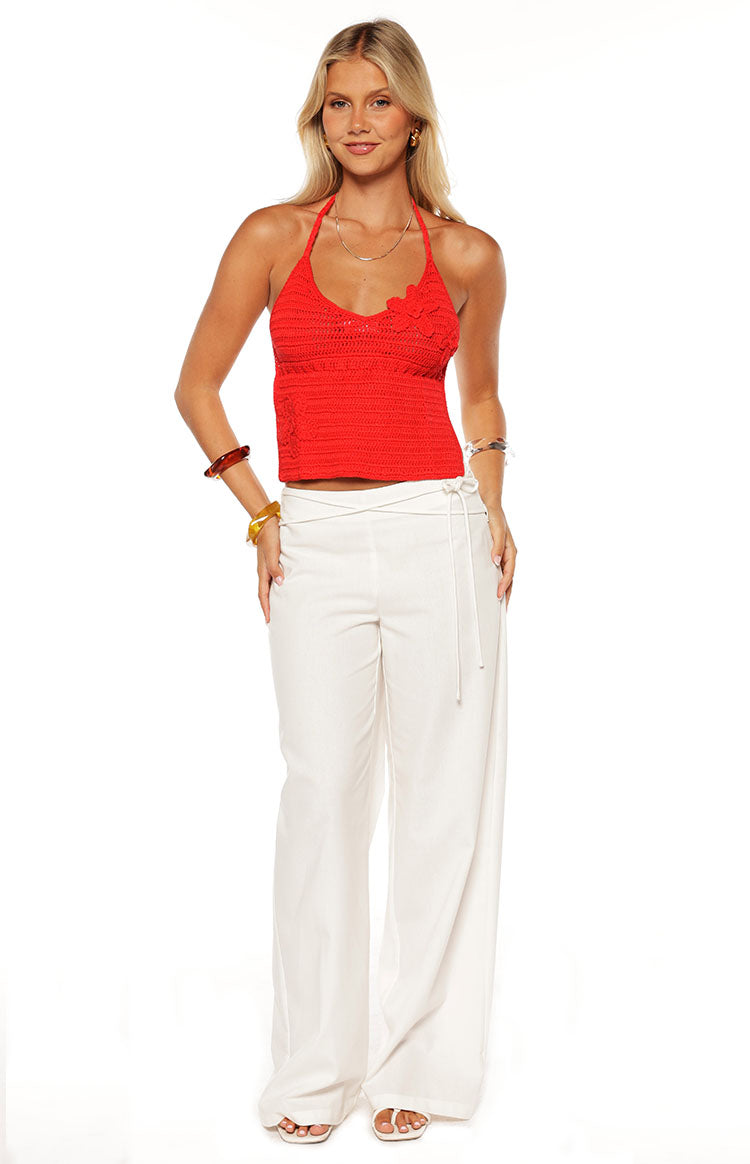 Front view of a red crochet halter top with floral applique on the bust and a cropped hem