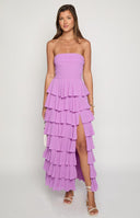 Brunette model wearing a strapless magenta gown with tiered details and a leg slit