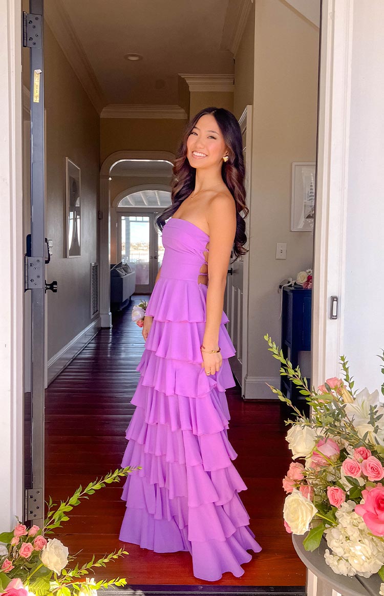 Side view of a lavender strapless maxi dress with tiered ruffles and a lace-up side bodice detail