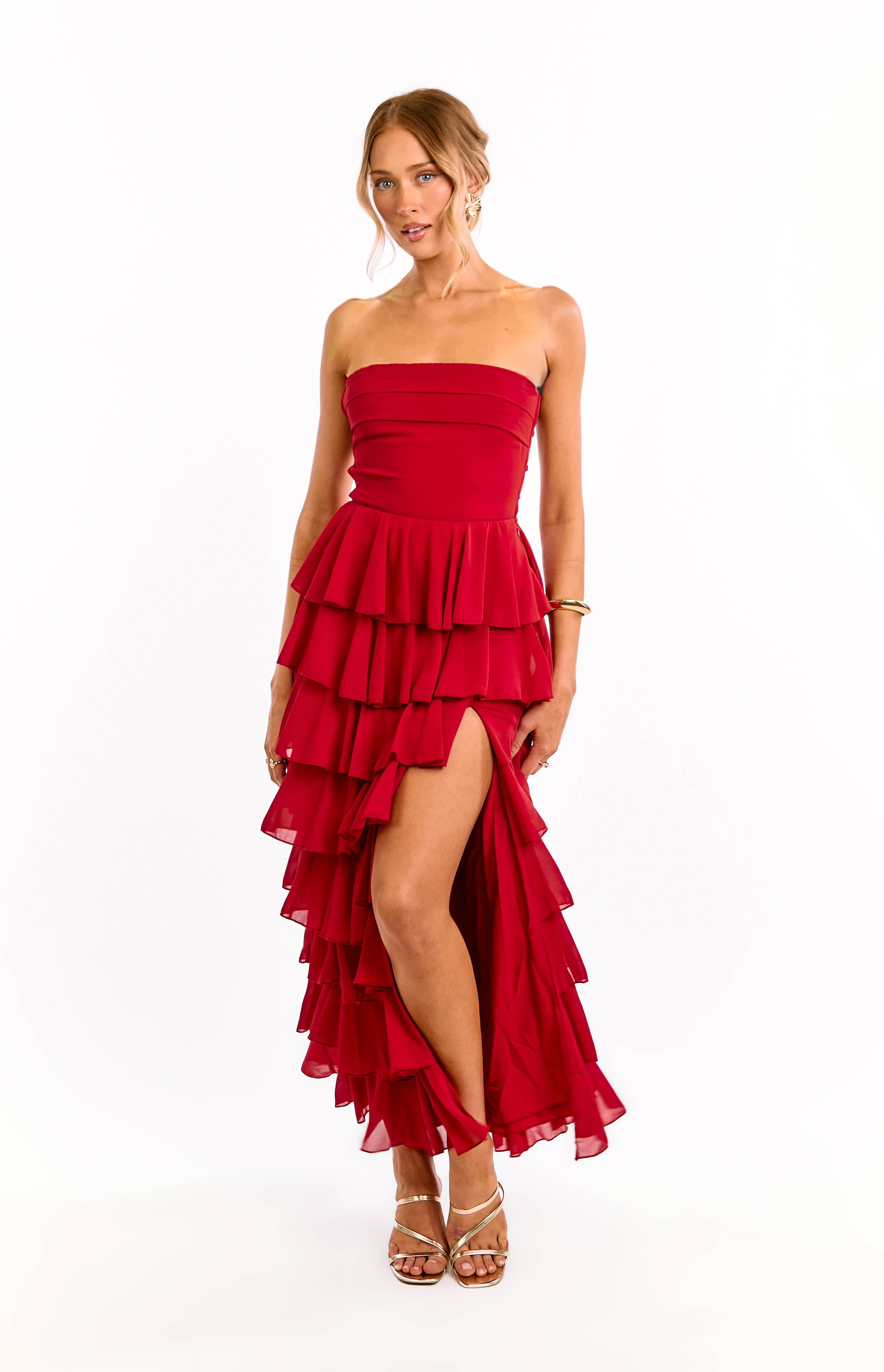 Front view of a red strapless maxi dress with a fitted bodice, tiered ruffles, and a high leg split