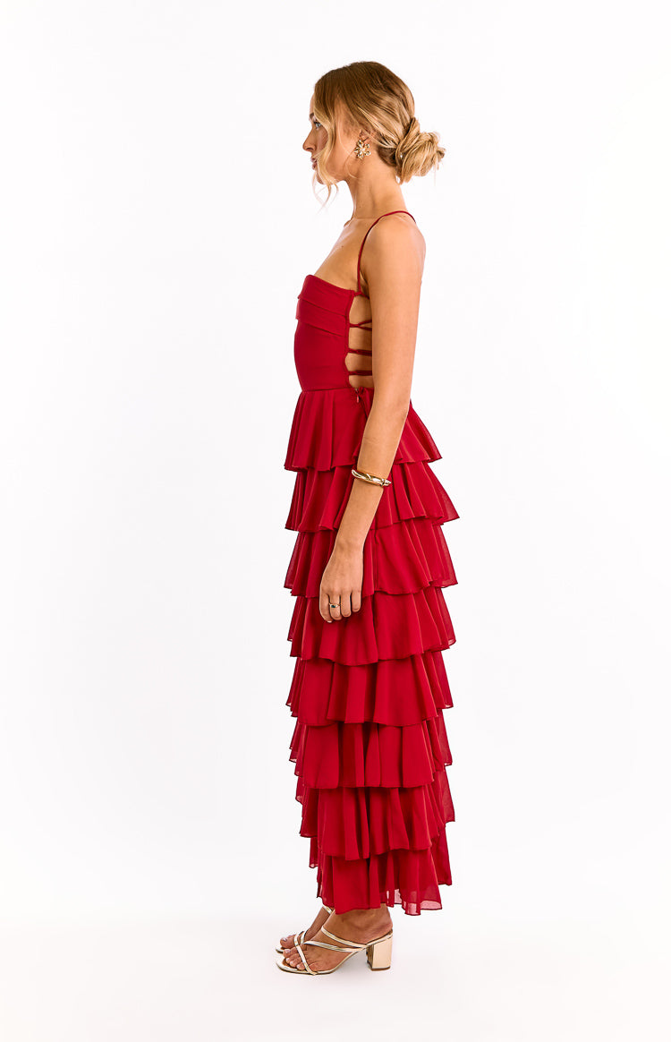 Side view of a red maxi dress featuring thin spaghetti straps, side cutouts with lacing, and a full tiered ruffle skirt