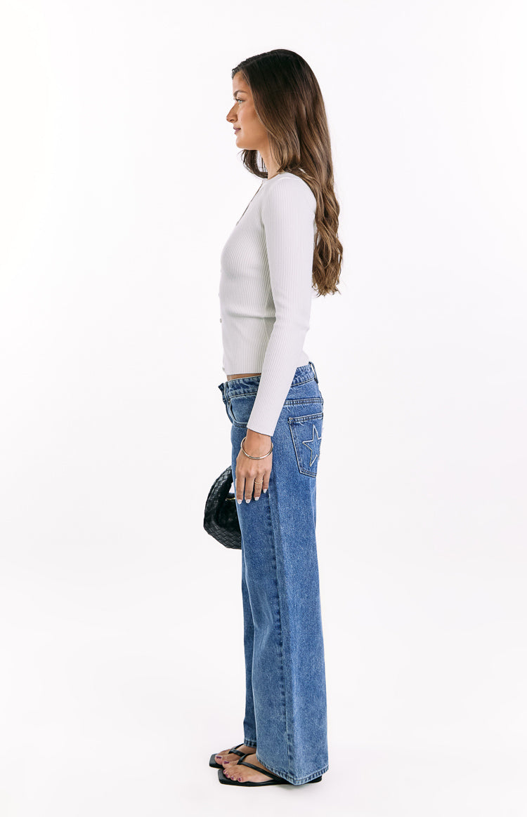 Side view of a white ribbed knit long sleeve sweater with a fitted silhouette and button-up front