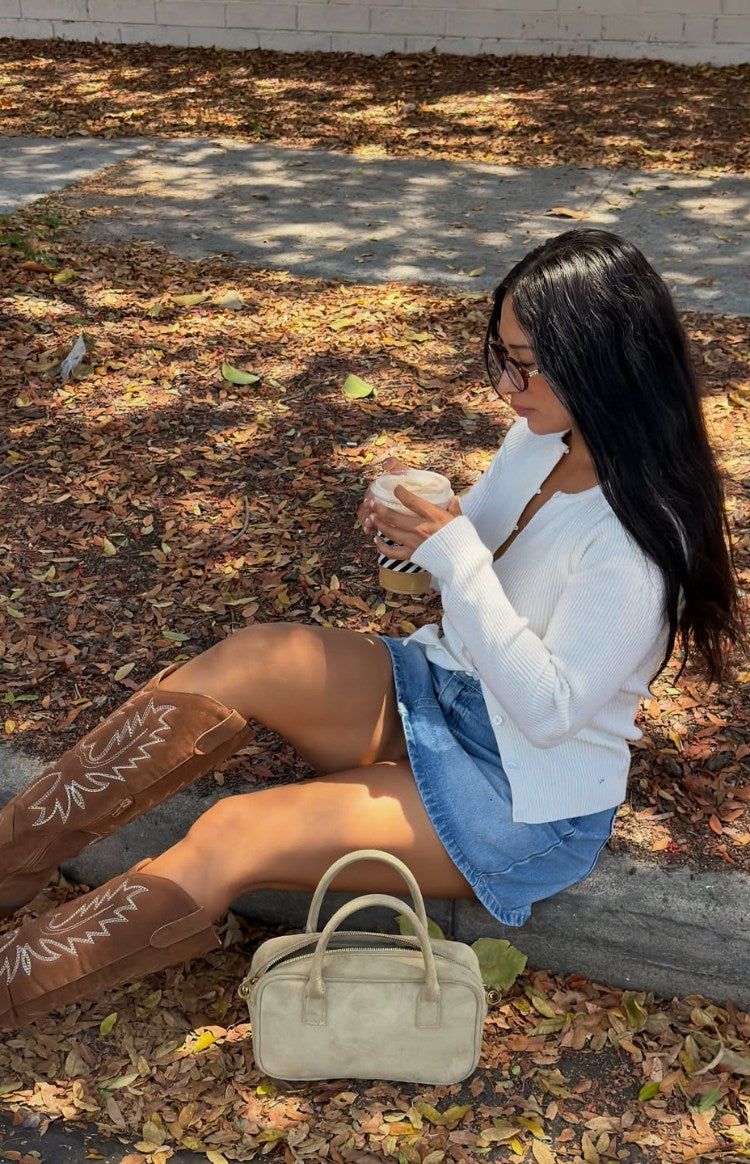Side view of a white ribbed knit long sleeve sweater with a V-neckline from unbuttoned front