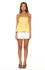 Front view of a textured yellow strapless top with a fitted bodice and a gathered peplum hem