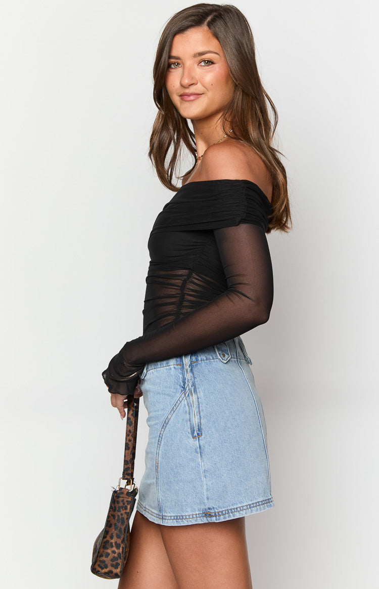 Side view of a light wash denim mini skirt with an A-line silhouette and a subtle angled front seam