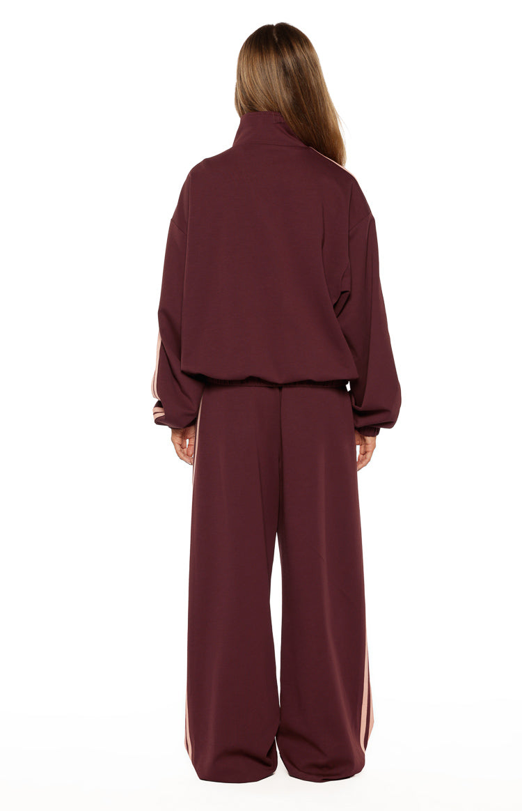 Rear view of burgundy wide-leg track pants with pink stripes down the side seams