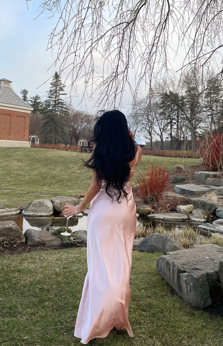 Rear view of the light pink satin maxi dress, highlighting its flowing silhouette and delicate spaghetti straps