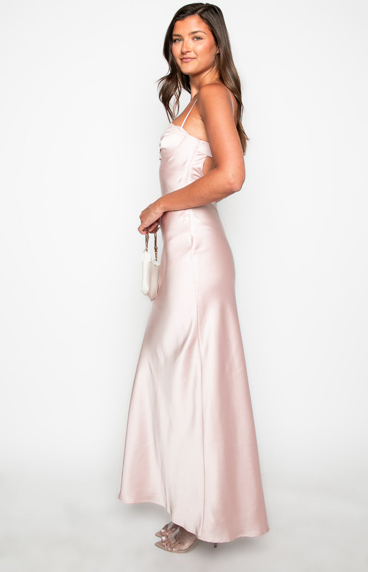 Side view of a pink satin maxi dress showing the side cutouts and ruched bust with thin straps