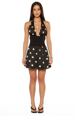 Front view of a black polka dot mini dress with a deep V-neck halter and wide solid black waistband