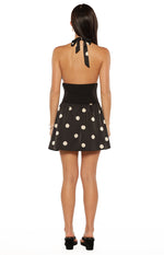 Rear view of a black halter neck mini dress with a tie-back and white polka dot skirt