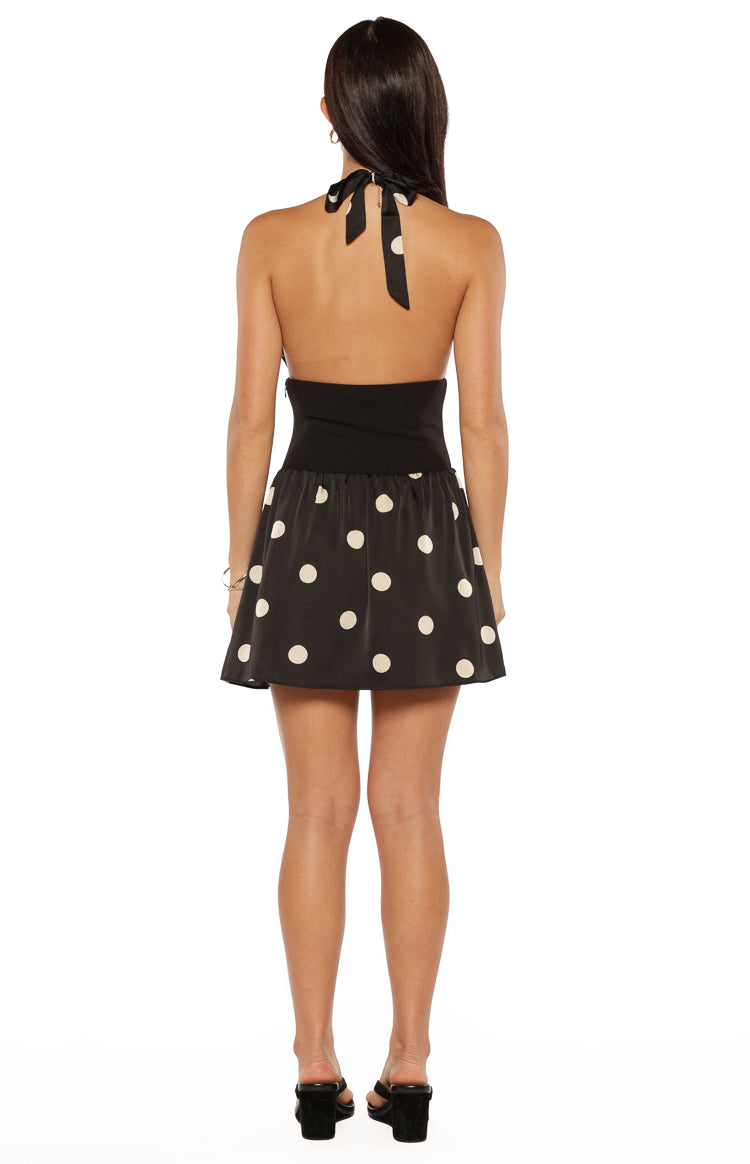 Rear view of a black halter neck mini dress with a tie-back and white polka dot skirt