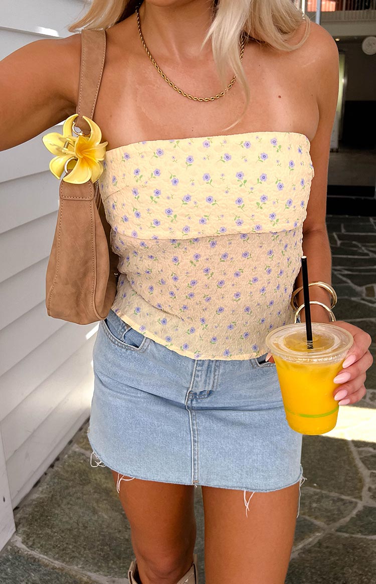 Close-up of the yellow floral strapless top showing crinkled texture and small purple flowers