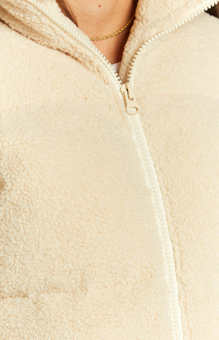 Detail shot of the cream teddy puffer jacket's full-length zipper and plush sherpa fabric