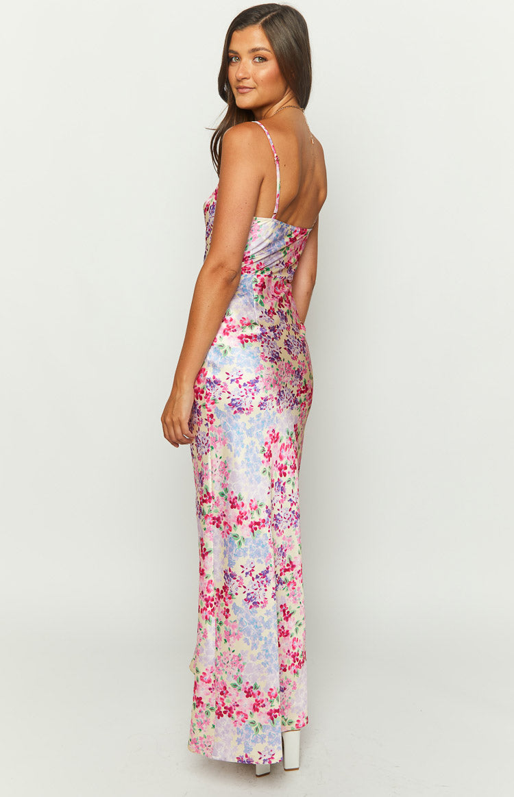 Side view of a light yellow satin maxi dress with vibrant pink and purple floral print, thin spaghetti straps, and a flowing skirt
