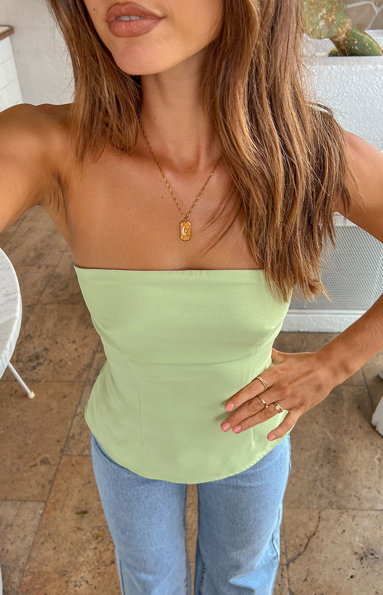 Close-up of a light green strapless top with a fitted bodice, visible seam details, and a curved hem