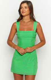 Front view of a fitted green mini dress with a subtle check texture, square neckline, and ruched wide straps