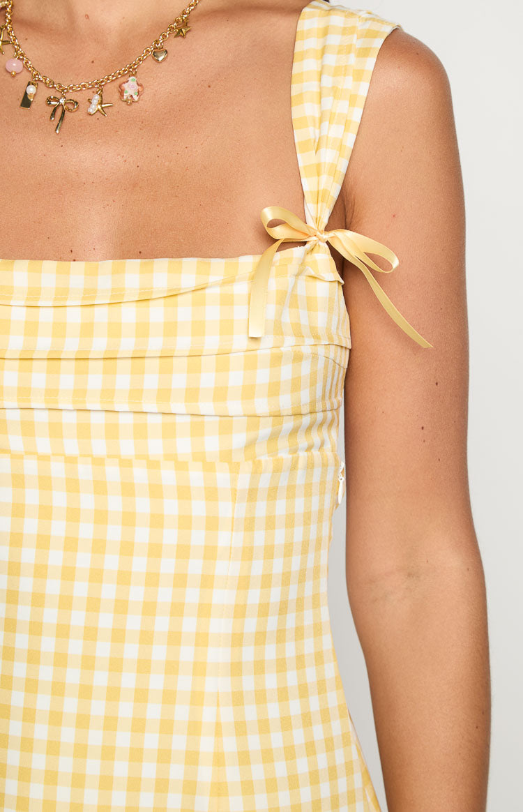 Yellow gingham dress detail showing the tied shoulder strap with a ribbon bow and pleated bodice