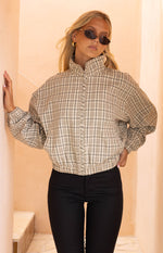 Beige plaid funnel neck jacket with a braided detail along the front zipper and elasticated hem