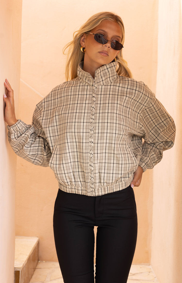 Beige plaid funnel neck jacket with a braided detail along the front zipper and elasticated hem