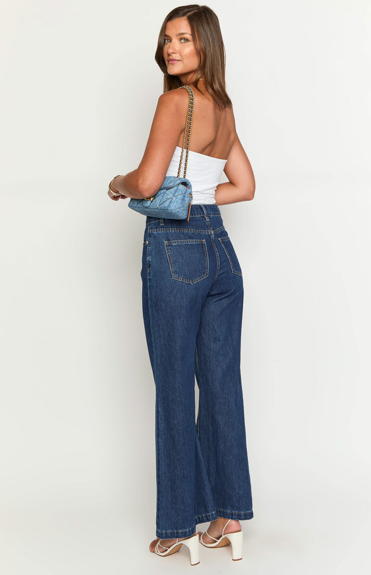 Rear-side view of dark blue denim flare jeans, showing the high-rise waist and classic patch pockets