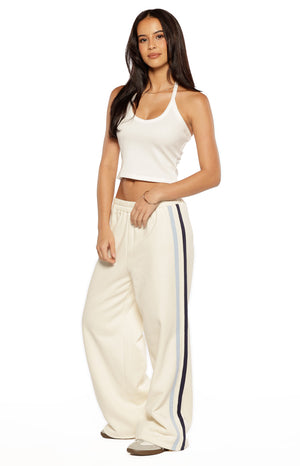 Full view of off-white wide-leg pants with light blue and navy contrast stripes down the side and an elastic waist