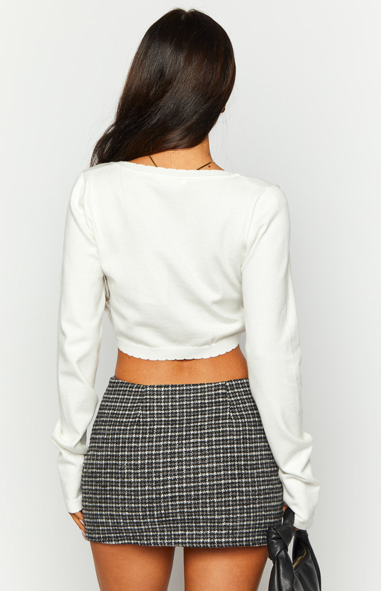 Rear view of a white long sleeve crop top with a scoop back and scalloped hem