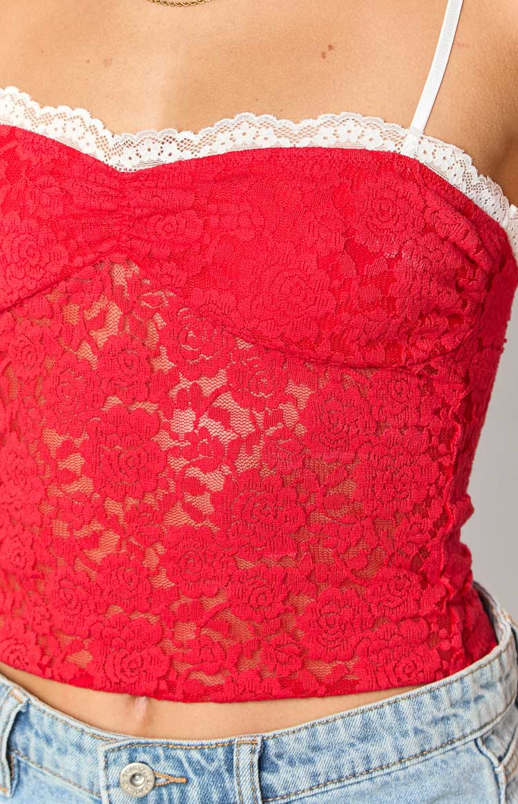 Close-up of the red floral lace fabric with white lace trim along the bust and a thin white spaghetti strap