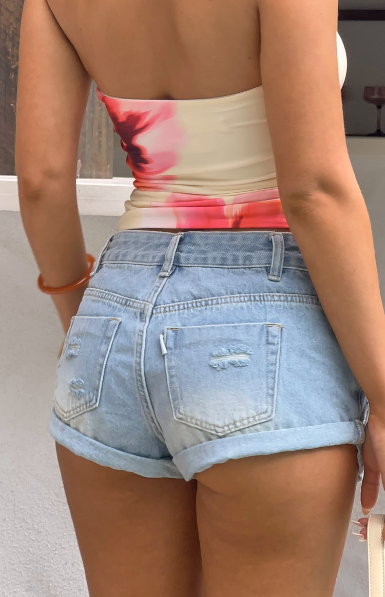 Rear view of light wash denim shorts with distressed back pockets and cuffed hems