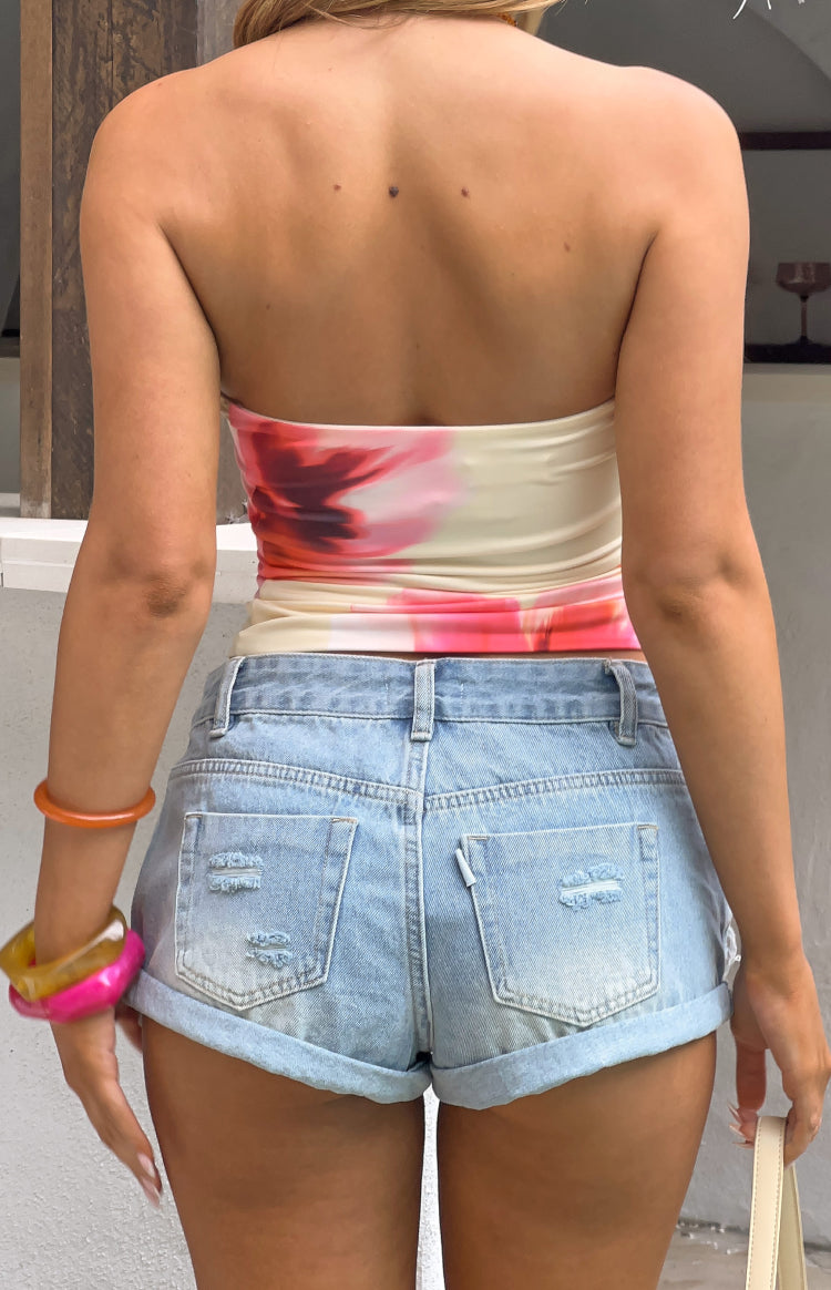 Rear view of light wash denim shorts with distressed back pockets and rolled cuffs