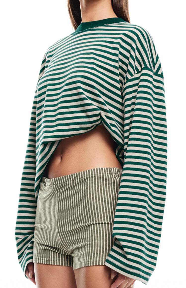 Close-up of the cropped hem and oversized fit of a green and white striped long sleeve top