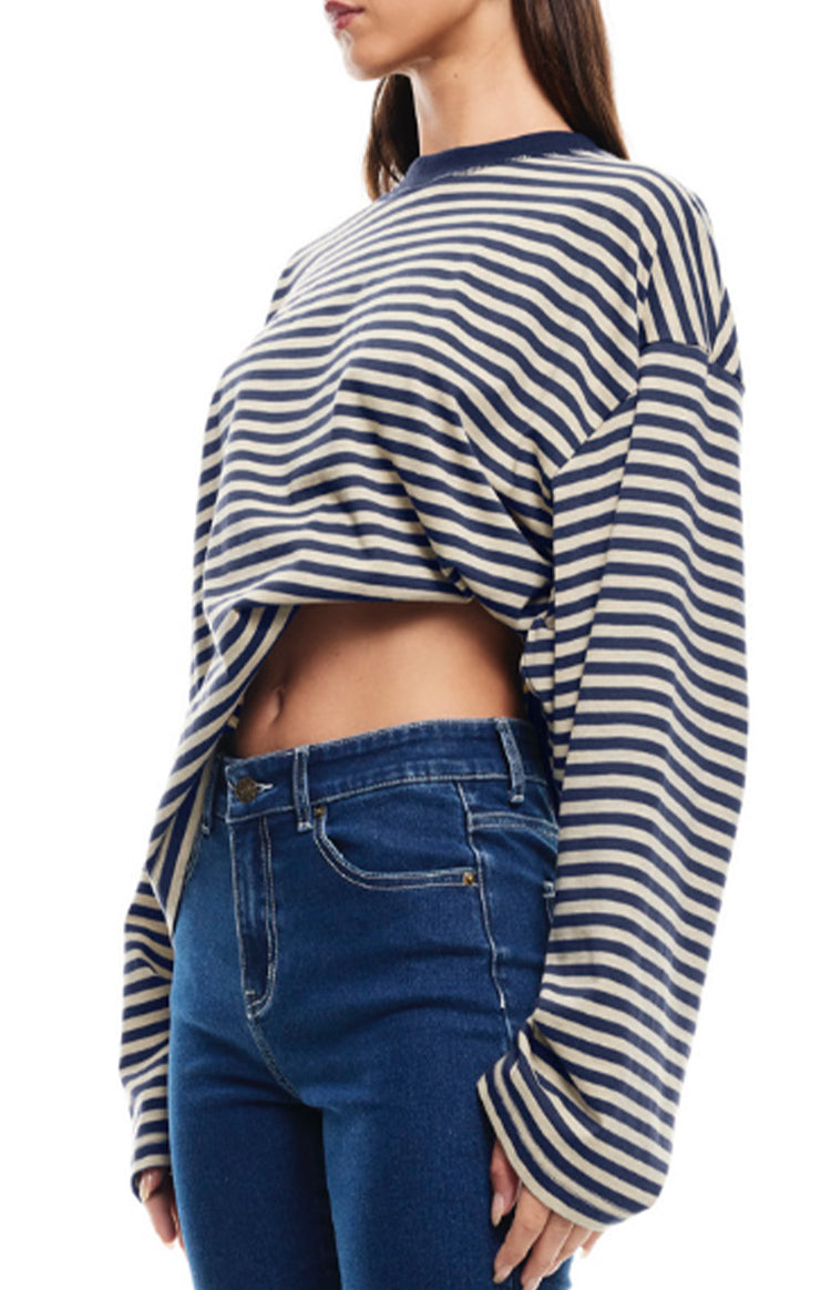 Side view of a navy and cream striped long sleeve top with a cropped hem and relaxed, oversized sleeves