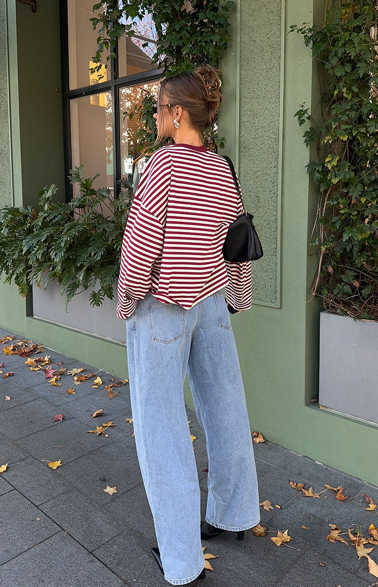 Rear-side view of an oversized wine stripe long sleeve top with dropped shoulders and a rounded hem