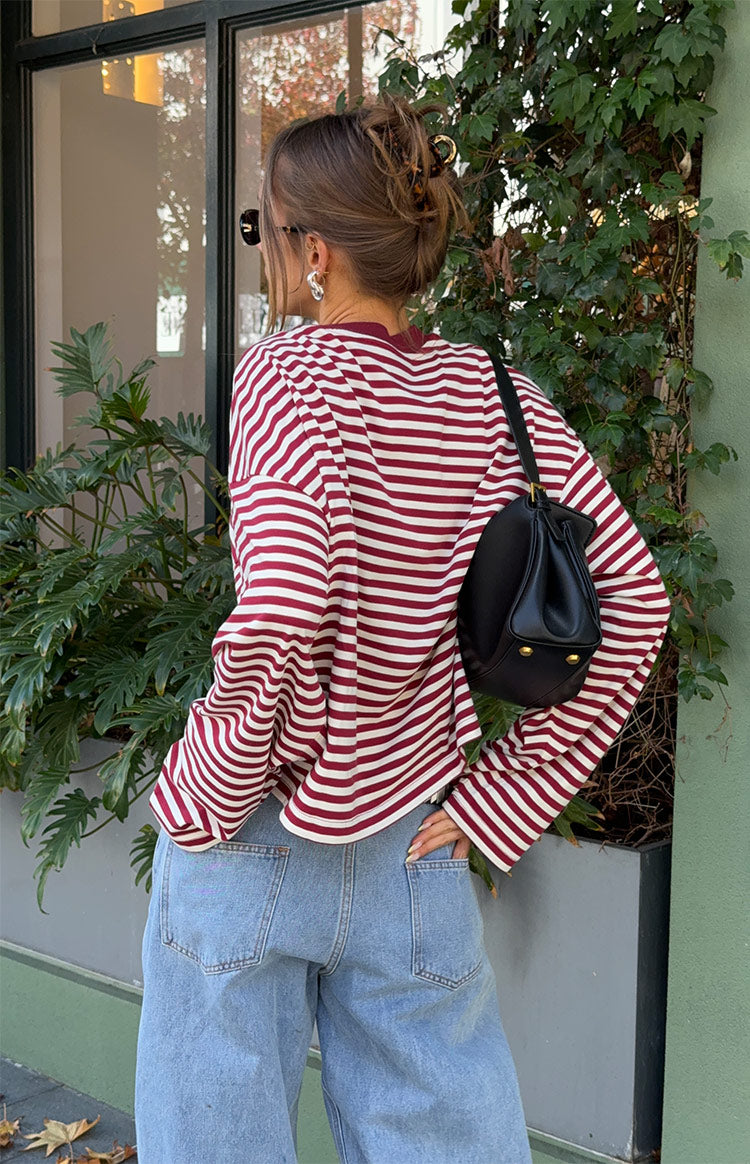 Rear view of a wine and white striped long sleeve top with a relaxed fit, crew neck, and curved hem