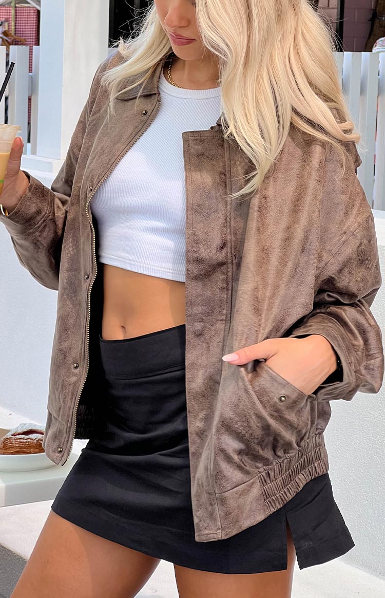 Close-up of the chocolate bomber jacket's distressed texture, open front zipper, and snap button pockets