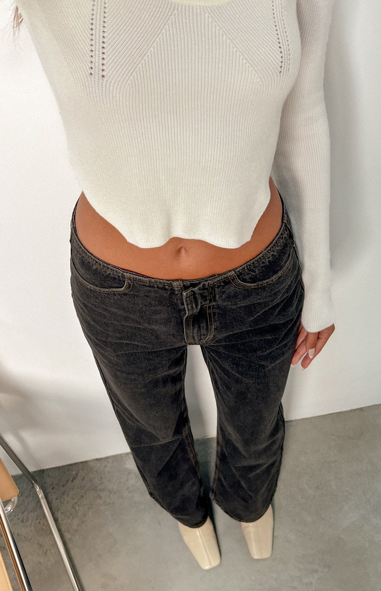 Close-up of the low-rise waist and front button fly of charcoal washed denim jeans